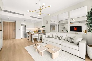 Ein modernes Wohnzimmer mit Sofa, Couchtisch und an der Wand montiertem Fernseher.