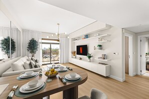 Ein modernes Wohnzimmer mit Essbereich, einem an der Wand befestigten Flachbildfernseher und einem Balkon mit Blick.