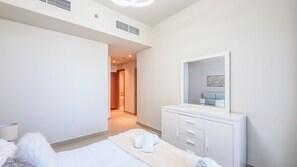 A hotel room with a bed, a bedside table, a mirror, and a wardrobe. - Harbour Gate Residences - Creek Harbour (Dubai)