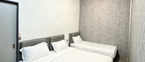 A hotel room with two beds, a door, and a wall with a textured pattern.
