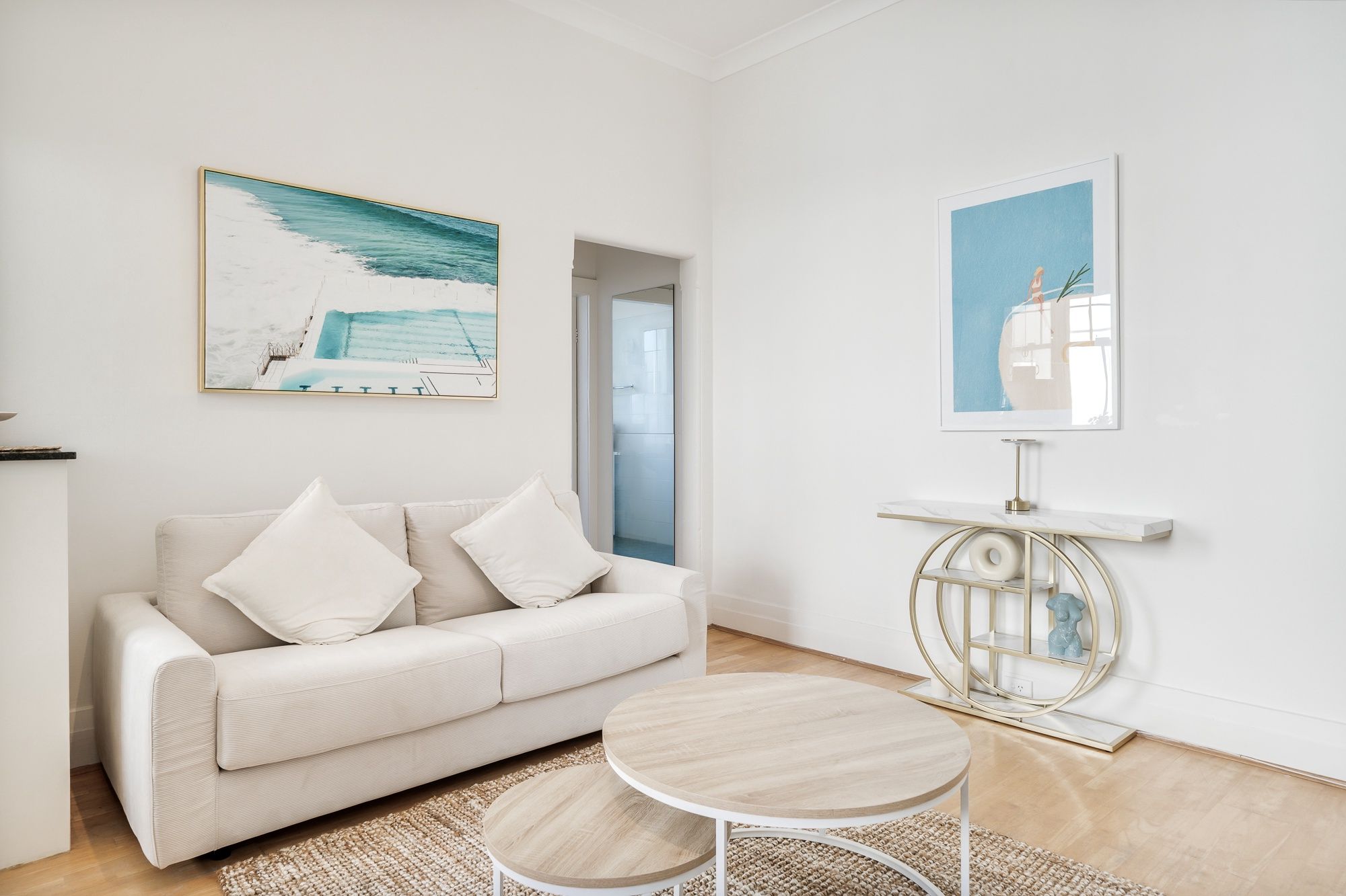 Een moderne woonkamer met een bank, twee ronde tafels en kunst aan de wanden.