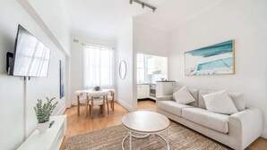 Un salon moderne comprenant un canapé, une table basse ronde et un coin repas avec une table et des chaises.