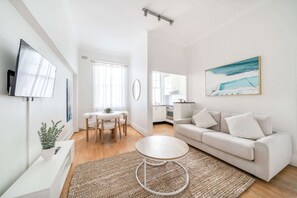 Ein modernes Wohnzimmer mit einer Couch, einem runden Couchtisch und einem Essbereich mit Tisch und Stühlen.