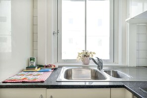 Eine Küche mit Fenster, Spüle und Arbeitsplatte, auf der sich eine Pflanze und Lebensmittel befinden.