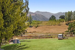 A grassy field with a tent, a picnic table, and a vehicle. - Maru Cabins at Sundale Holiday Park (Wānaka)