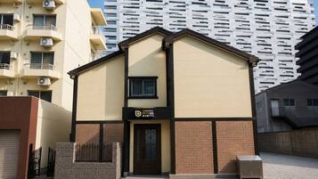 Un hotel con fachada moderna, un letrero que indica que es un hotel-apartamento y un edificio grande al fondo.