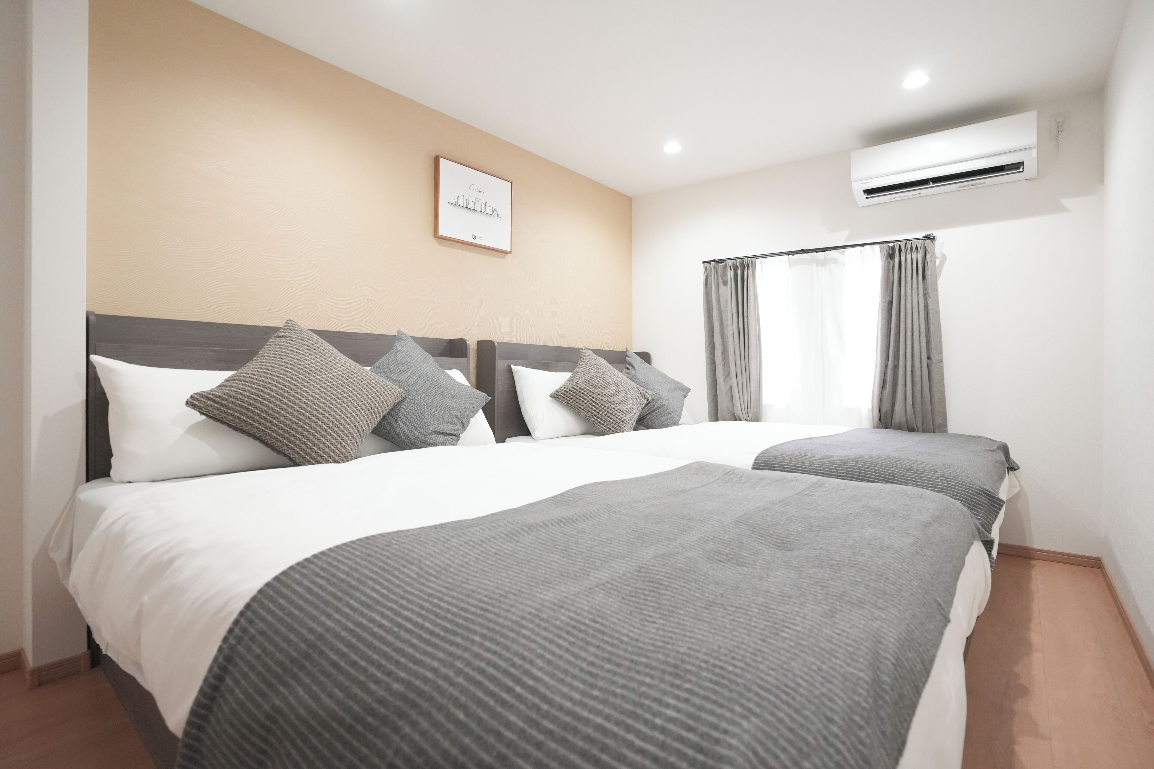A hotel room with two beds, a framed picture on the wall, and an air conditioning unit.