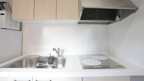 A kitchen with a stainless steel sink, a built-in stove, and a microwave above the counter. - b&Tsutenkaku3 (Osaka Naniwa-ku)