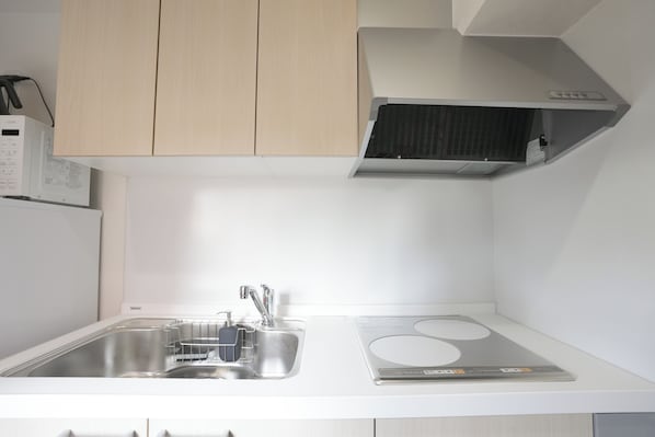 Una cocina con un lavamanos de acero inoxidable, una estufa integrada y un microondas sobre la encimera.