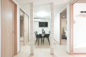 Un interior modern amb zona de dinar, televisió de pantalla plana penjada a la paret i un passadís que condueix a una habitació.