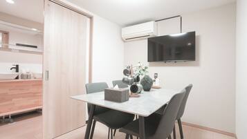 Un comedor moderno con una mesa, sillas, un florero y un televisor montado.