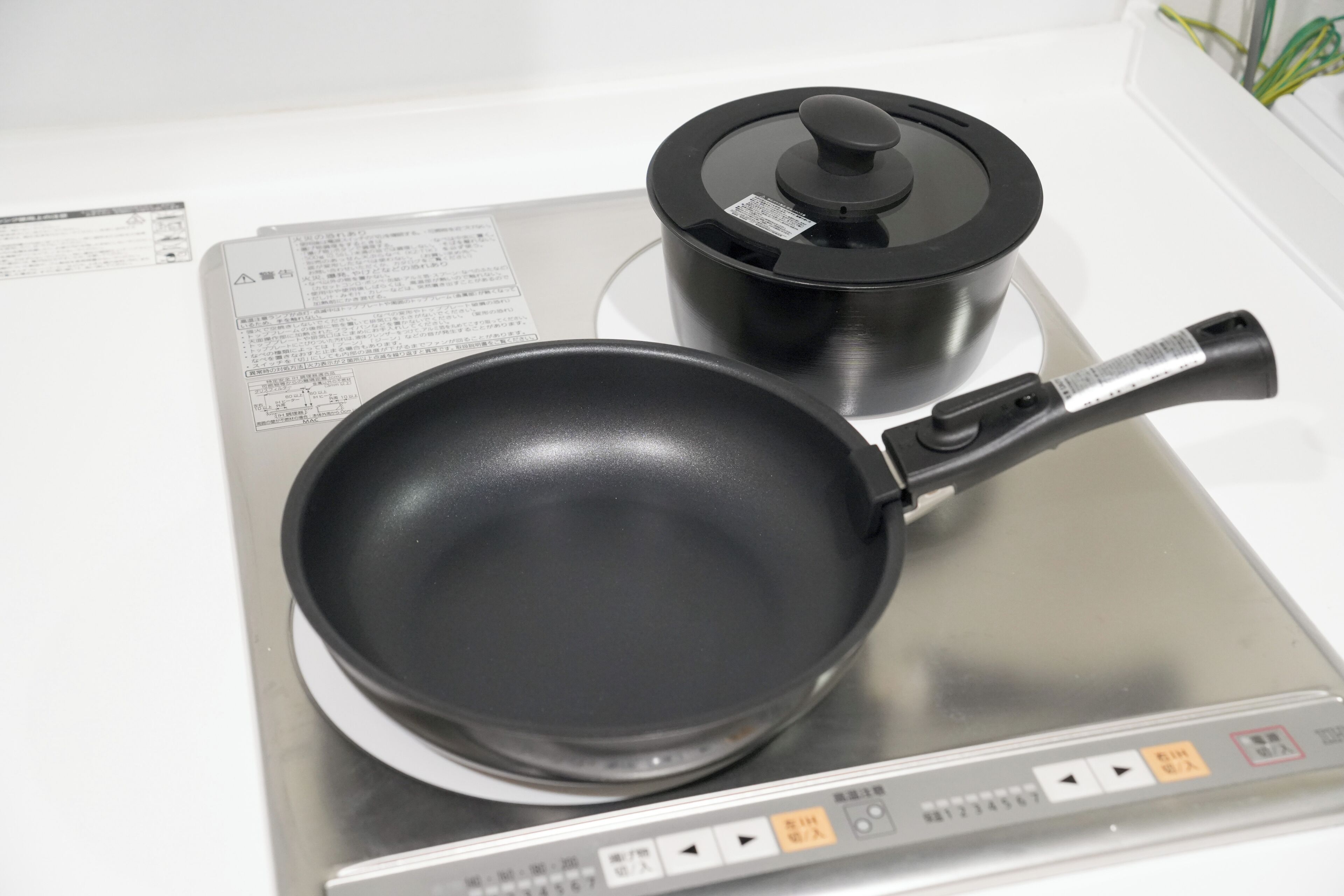 A kitchen with a stove, a frying pan, and a pot.