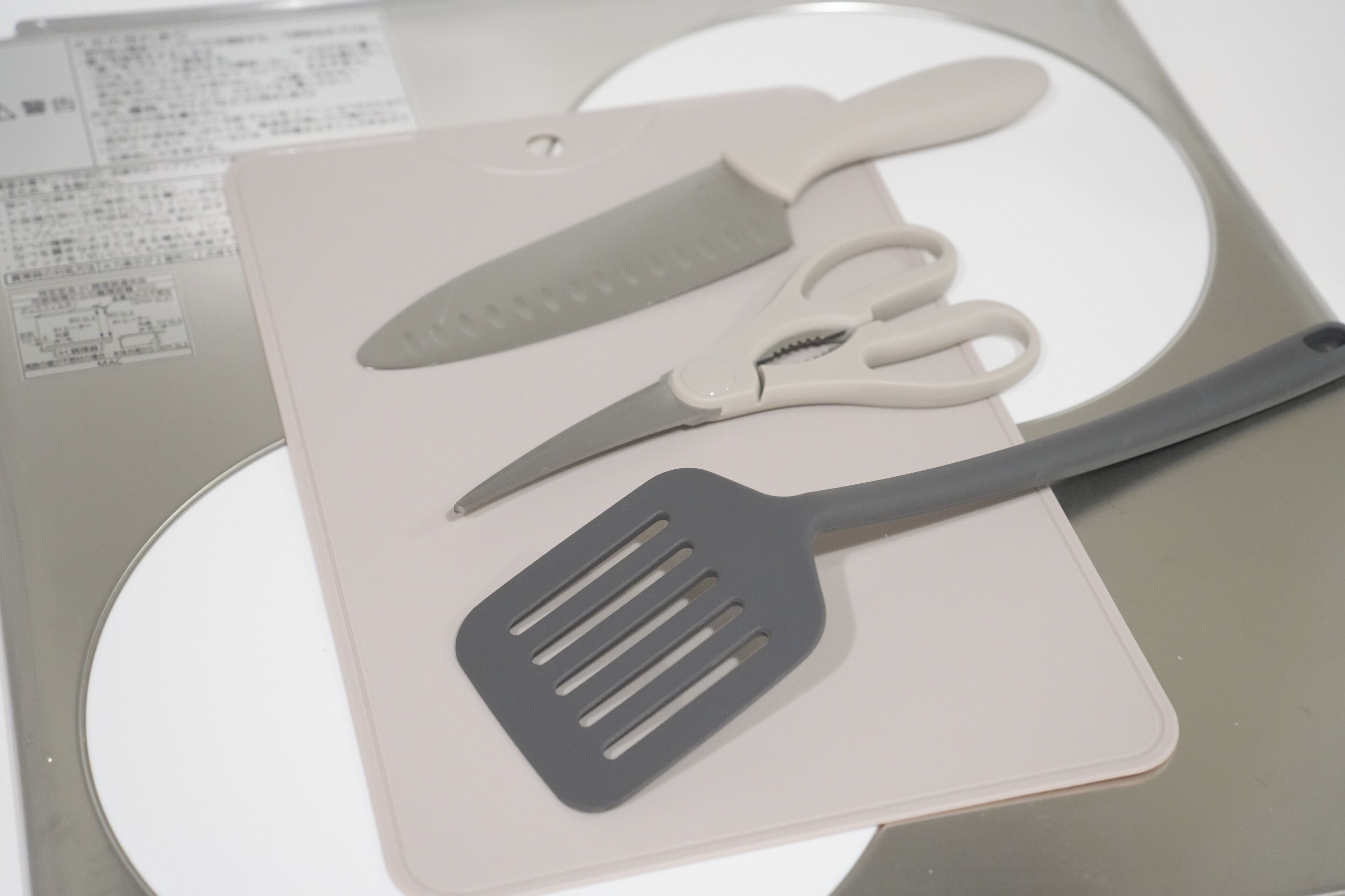 A kitchen utensil set on a white surface with a printed sheet of paper underneath.