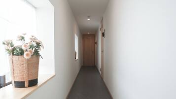 A narrow hallway with a carpeted floor, a window on the left, and a door at the end.