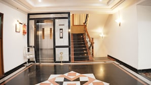 A hotel lobby with a staircase, a fire extinguisher, and a framed picture on the wall.