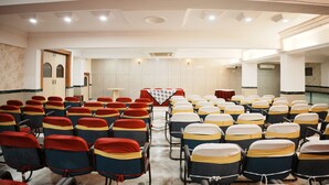 A conference room with rows of chairs, a table with a tablecloth, and a door.