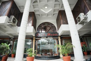 A hotel entrance with a sign reading 'Arch Manor,' large columns, and air conditioning units. - Arch Manor Bhopal (Bhopal)