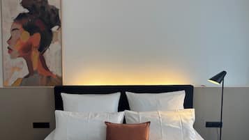 Ein Hotelzimmer mit einem Bett, Kissen, einem Bild an der Wand und einer Stehlampe.