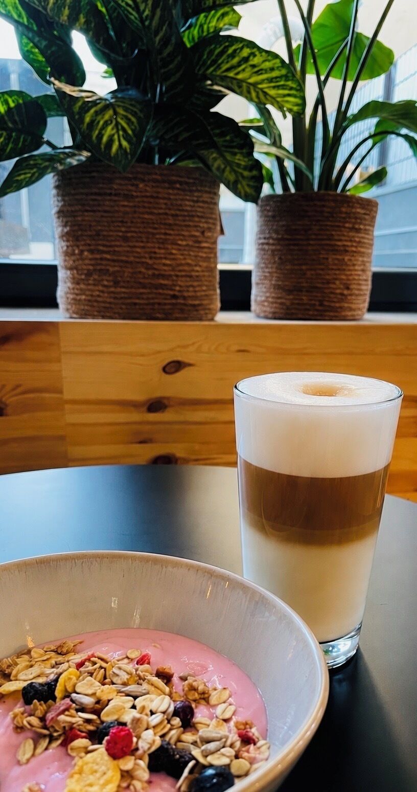 Una mesa con un vaso de leche y un tazón de granola con frutas.