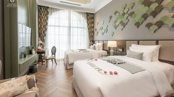 Une chambre d’hôtel avec deux lits, un bureau, une chaise et une grande fenêtre avec des rideaux.
