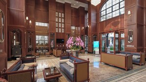 A spacious lobby with high ceilings, wooden paneling, and a large arched window.