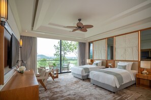 Habitación de hotel con dos camas, un escritorio, una silla, un televisor y un balcón con vistas.