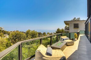 A balcony with a glass railing, a sofa, and a small table with cushions.