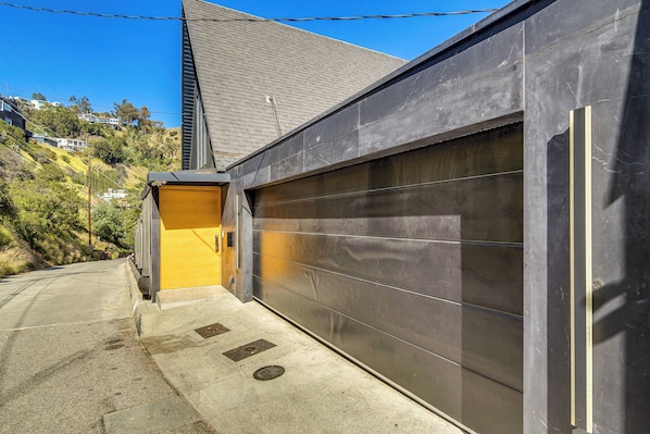 A modern building with a garage door, a small yellow door, and a sloped roof.