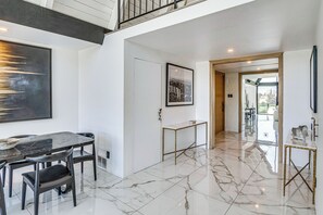 A modern interior with a dining area, a hallway, and a view of the outdoors.