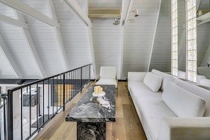 A modern interior with a marble table, white sofa, and a balcony with a railing.