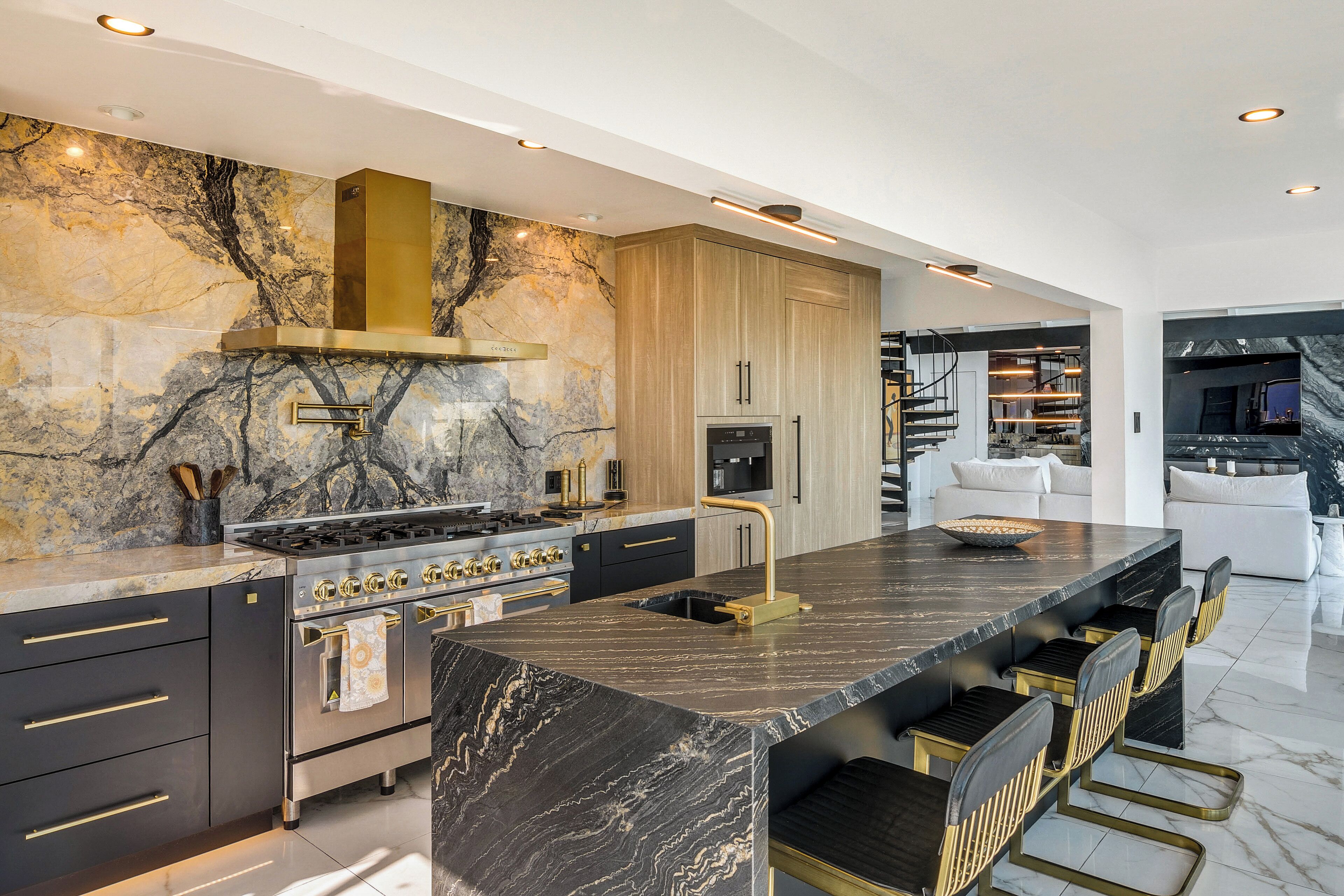 A modern kitchen with a central island, built-in oven, and marble backsplash.