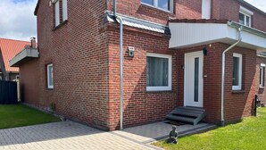 Een rode bakstenen woning met een witte deur, een klein voortuintje en een nummer 18.