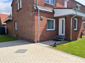 A red brick house with a white door, a small front porch, and a number 18 sign. - Apartment "Waldnähe" with Private Terrace, Garden, and Wi-Fi (Norden)