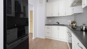 Een moderne keuken met witte kasten, een zwarte koelkast en een rvs afzuigkap.