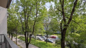 Een balkon met uitzicht op een parkeerplaats en bomen.