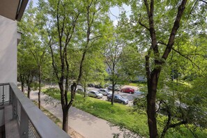 A balcony with a view of a parking lot and trees. - Comfortable Apartment with a Balcony  Near the Airport (Warsaw)