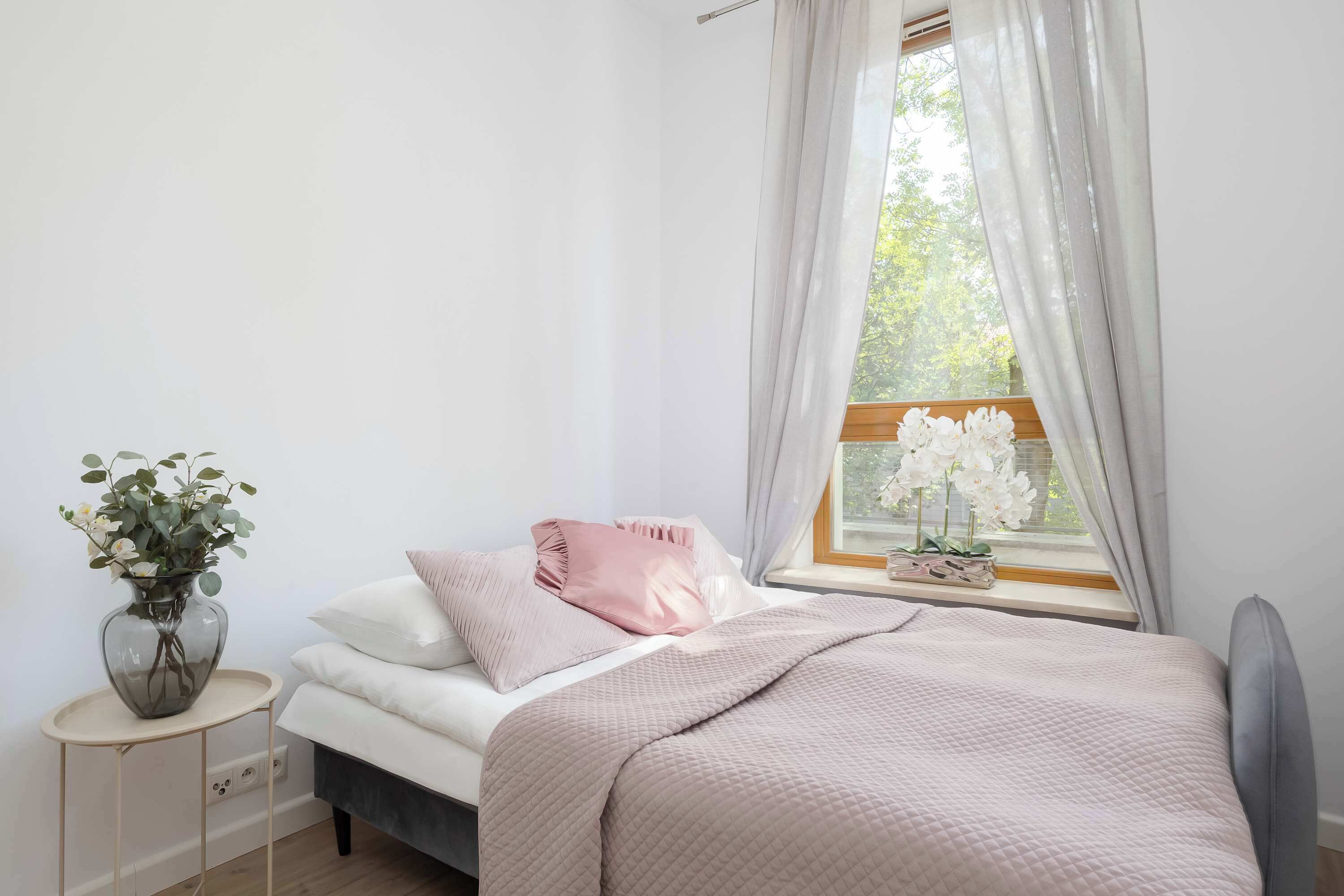 Ein Schlafzimmer mit Bett, Nachttisch und einem Fenster mit Vorhängen.