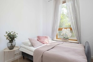A bedroom with a bed, bedside table, and a window with curtains. - Comfortable Apartment with a Balcony  Near the Airport (Warsaw)