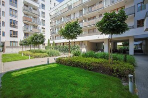 A modern apartment building with multiple balconies and a well-maintained garden area. - Comfortable Apartment with a Balcony  Near the Airport (Warsaw)