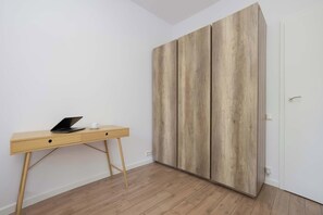 A room with a wooden desk, a laptop, and a wardrobe with a wooden finish. - Comfortable Apartment with a Balcony  Near the Airport (Warsaw)