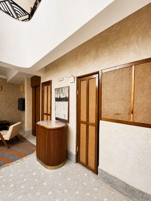 A hotel lobby with a round wooden table, a sofa, and a wall-mounted TV. - Riad 77 – A charming residence with a terrace and pool in the heart of the medina in Marrakech (Marrakesh)