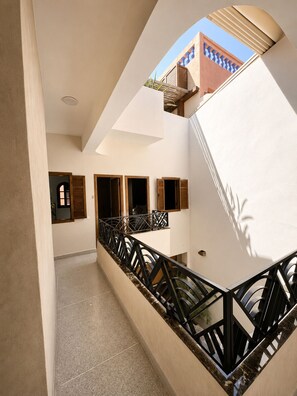 A modern interior with a central staircase, a balcony with a view, and a geometric ceiling design. - Riad 77 – A charming residence with a terrace and pool in the heart of the medina in Marrakech (Marrakesh)