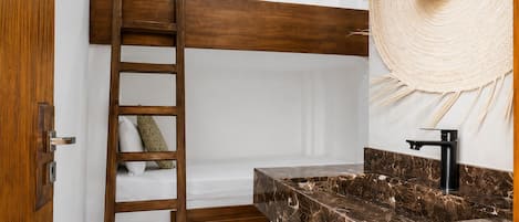 A bathroom with a wooden ladder, a marble sink, and a large woven hat hanging on the wall.