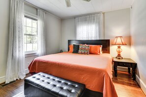 Une chambre à coucher avec un grand lit, une table de chevet avec une lampe et une fenêtre avec des rideaux.