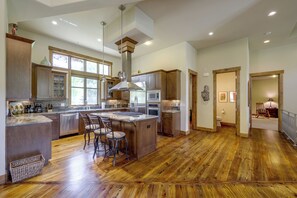 Uma cozinha espaçosa com ilha central, eletrodomésticos de aço inoxidável e uma grande janela que oferece iluminação natural.