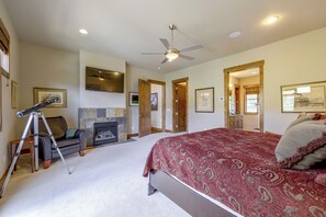 Um quarto com cama, lareira, telescópio e ventoinha no teto.