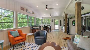 A spacious room with a dining area, a kitchen, and a seating area with a view of trees.