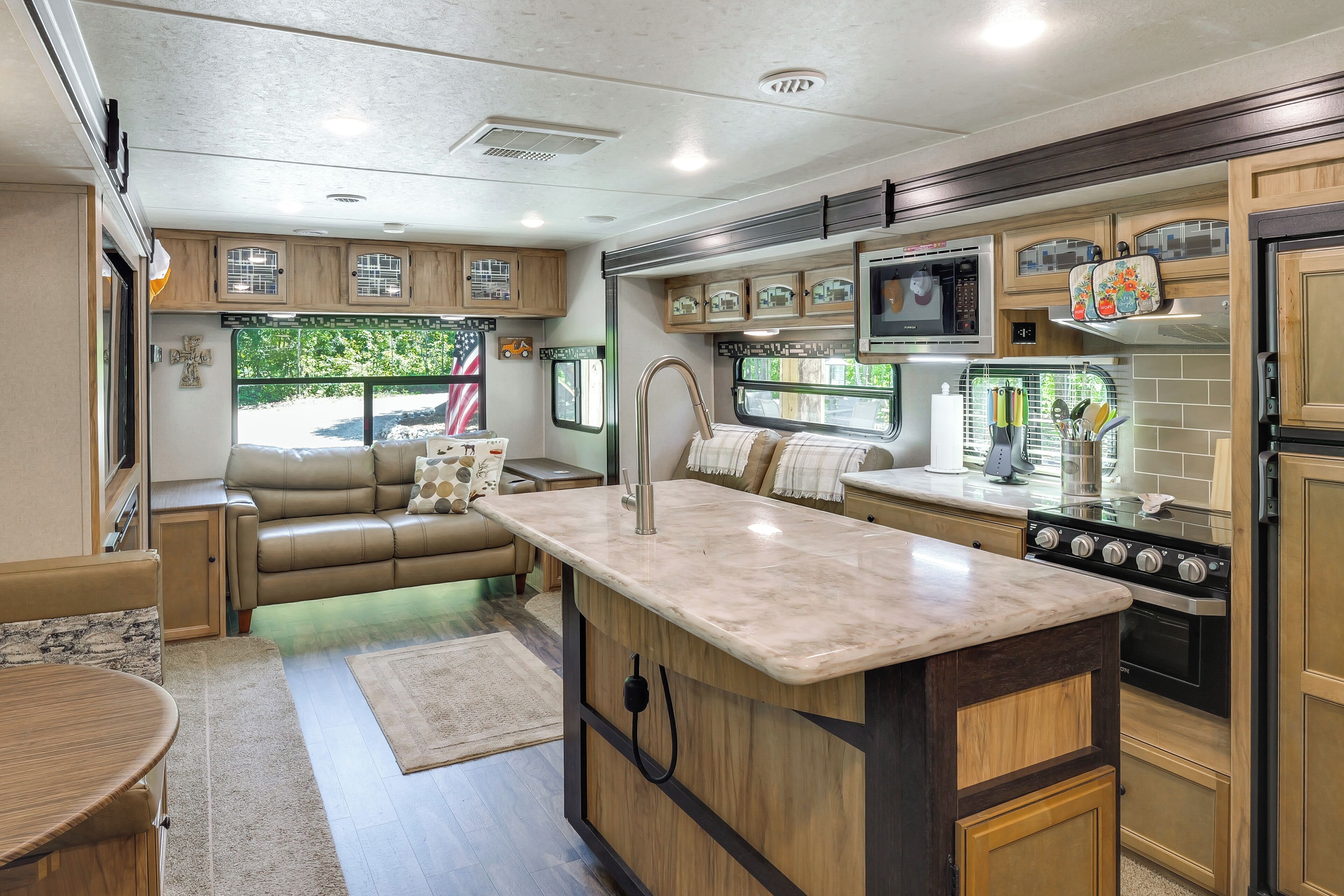 Cocina compacta para autocaravana con isla central, electrodomésticos integrados y zona de comedor.