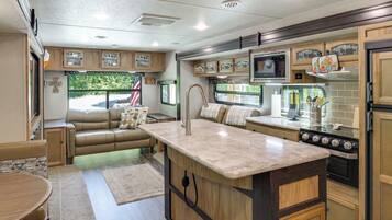 Cocina compacta para autocaravana con isla central, electrodomésticos integrados y zona de comedor.
