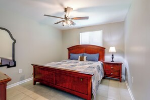 A bedroom with a wooden bed, a nightstand with a lamp, a ceiling fan, and a window with blinds. - < 1 Mi to LSU Campus! Game Day Hub in Baton Rouge (Baton Rouge)